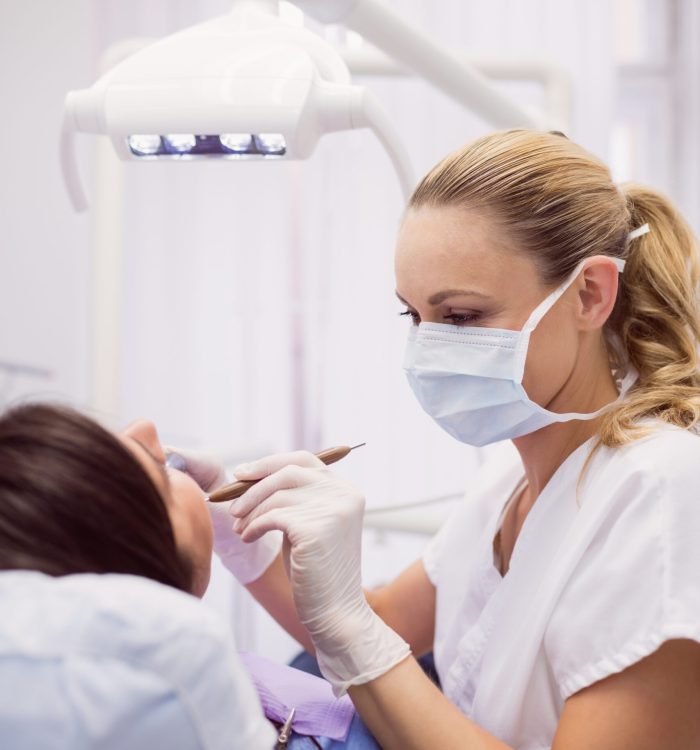 Dentist examining female patient in clinic